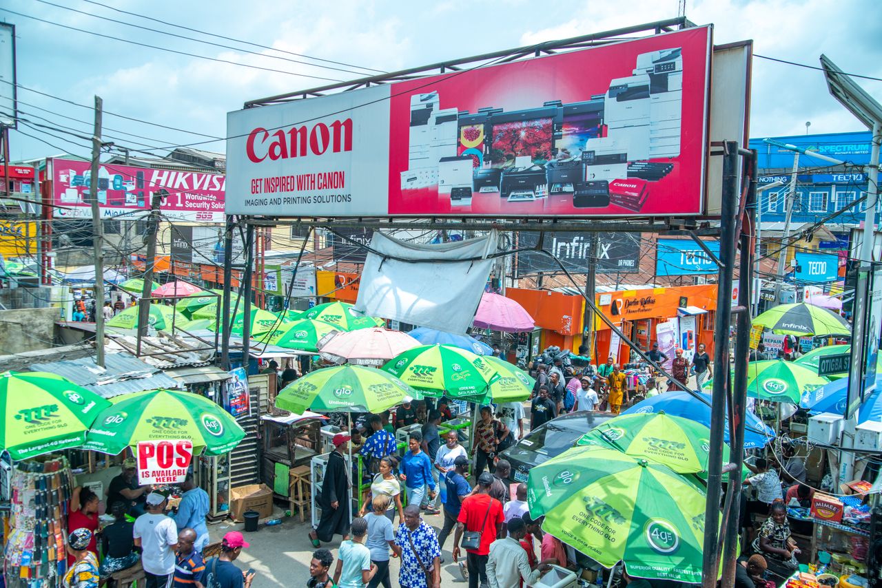 Busy Lagos market street lined with shops and small businesses competing for customers