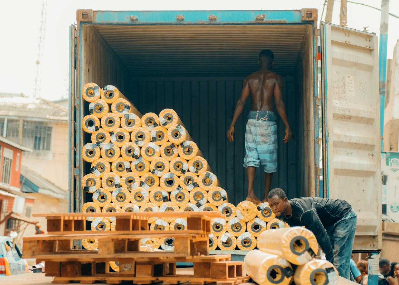 Workers offloading and organising goods from a shipping container at a Nigerian logistics operation